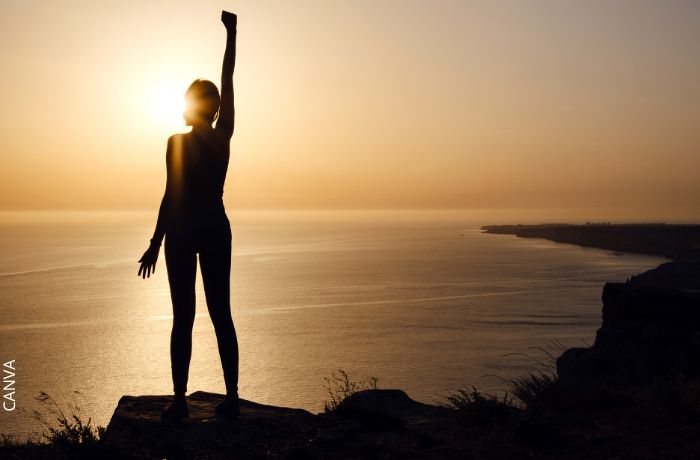 Foto de una mujer levantando la mano frente al sol
