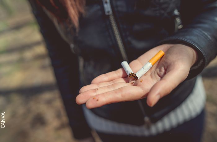 Foto de un cigarrillo partido en la mano de una mujer