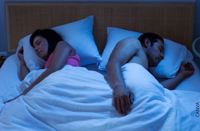 Foto de una pareja durmiendo de espaldas